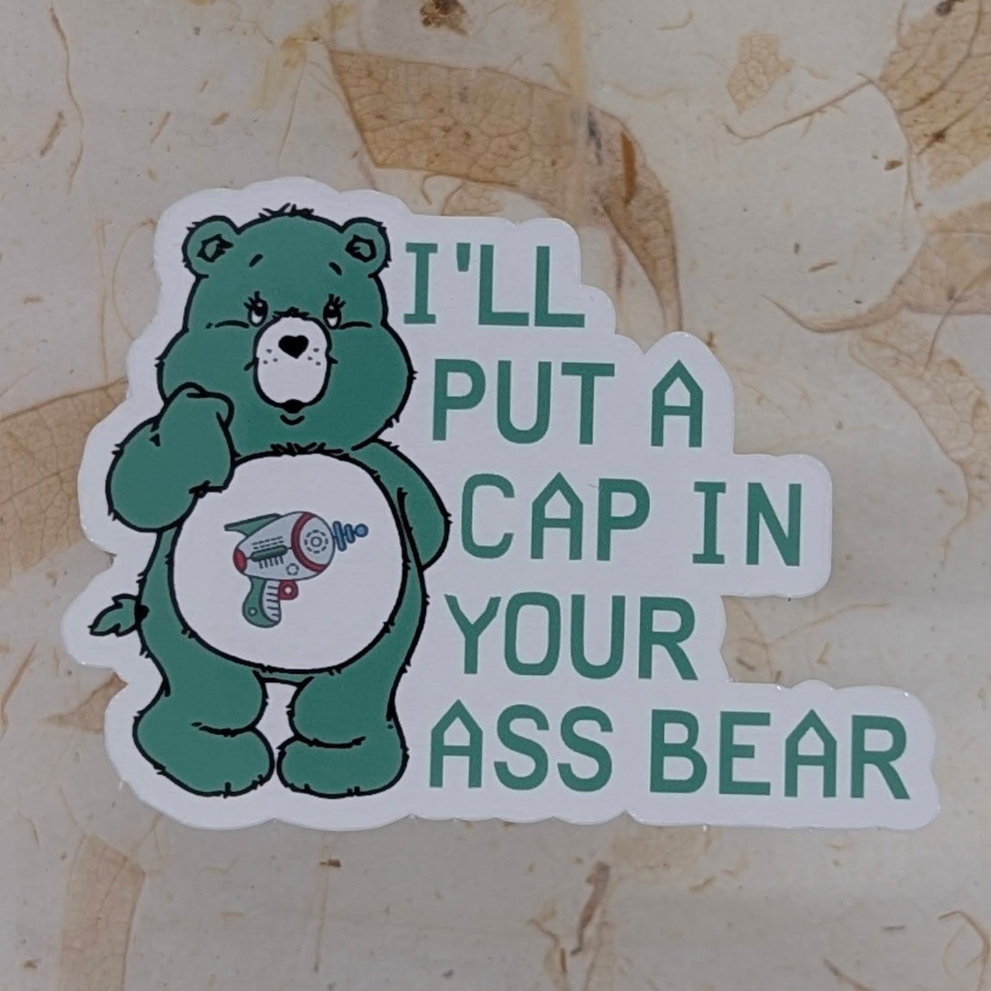 Sticker with a green bear character and text on a textured beige background