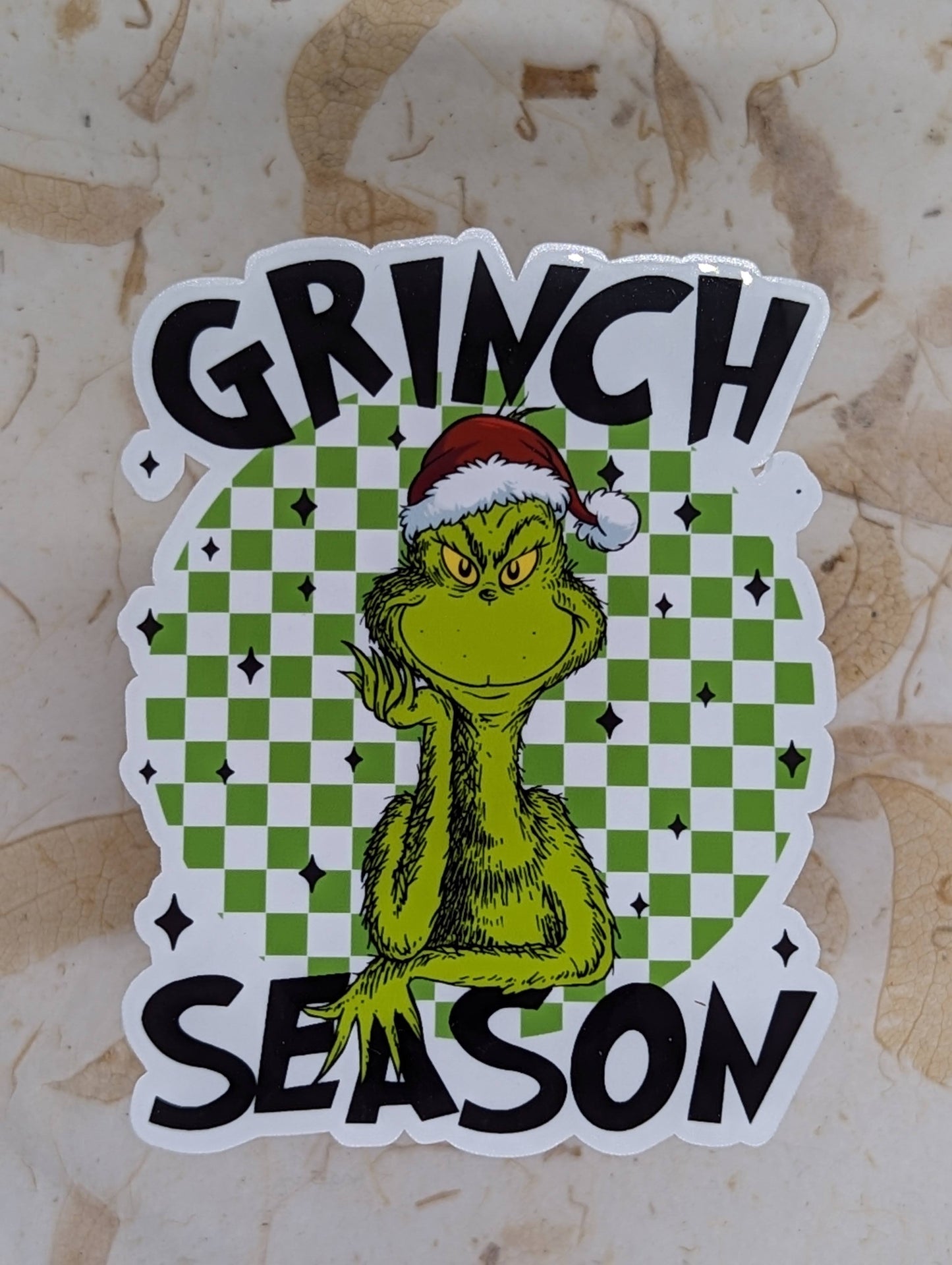 Sticker with Grinch design and 'Grinch Season' text on a checkered background