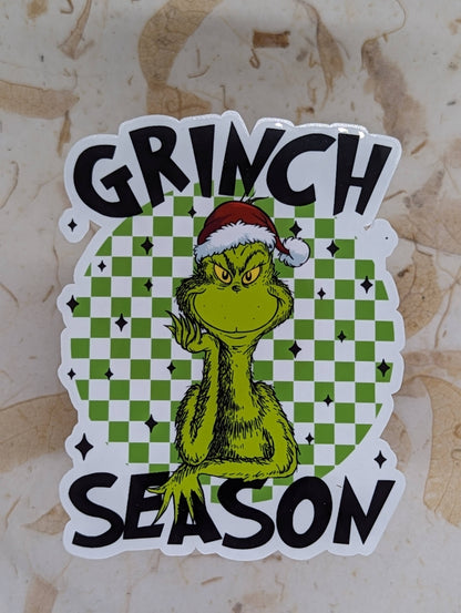 Sticker with Grinch design and 'Grinch Season' text on a checkered background