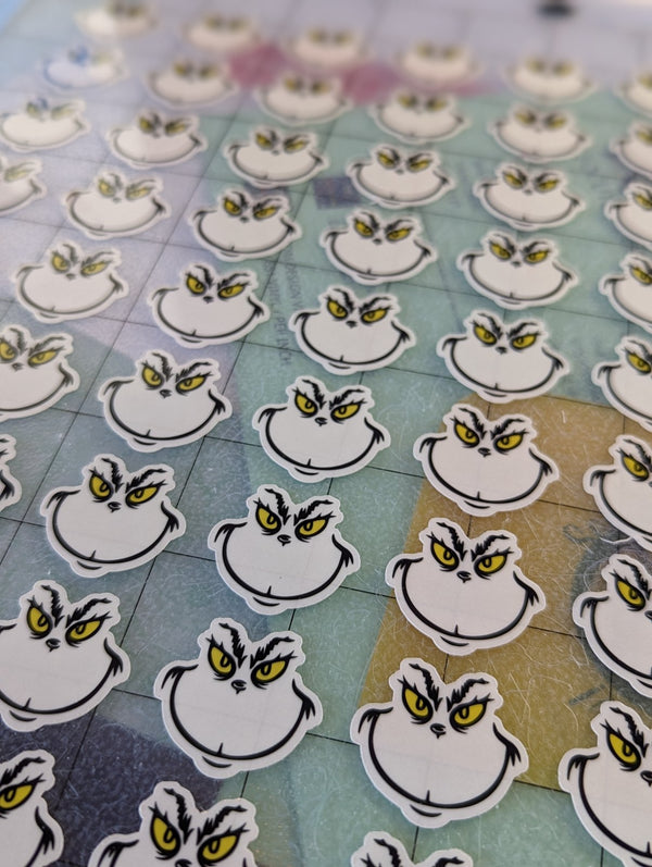 Tiny grumpy Christmas face stickers on the cutting mat