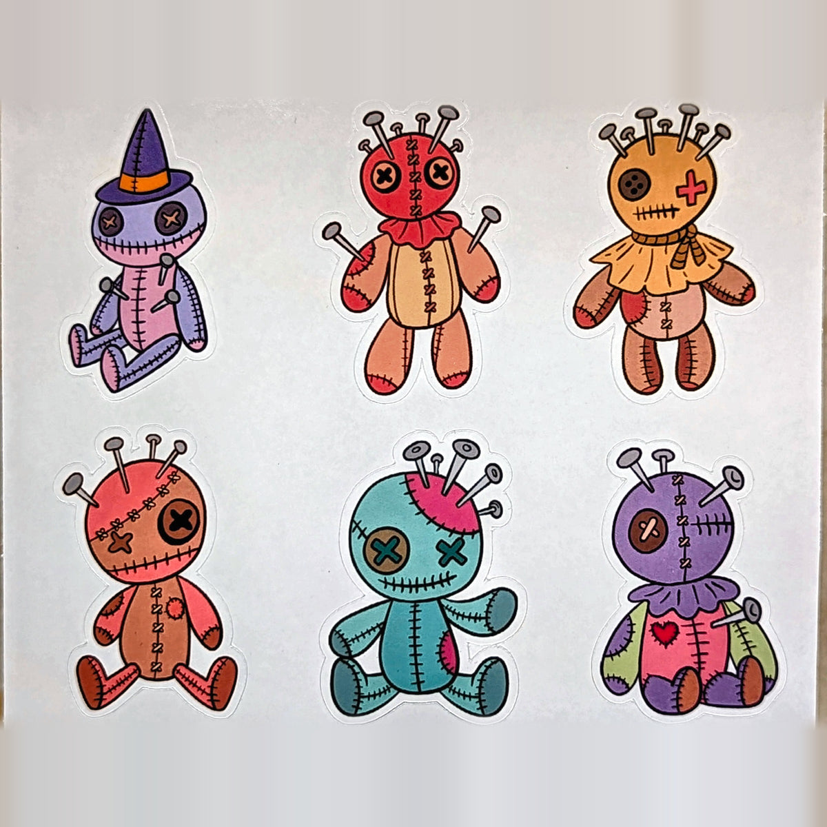 Close-up of six voodoo doll stickers including witch hat doll, real product photo
